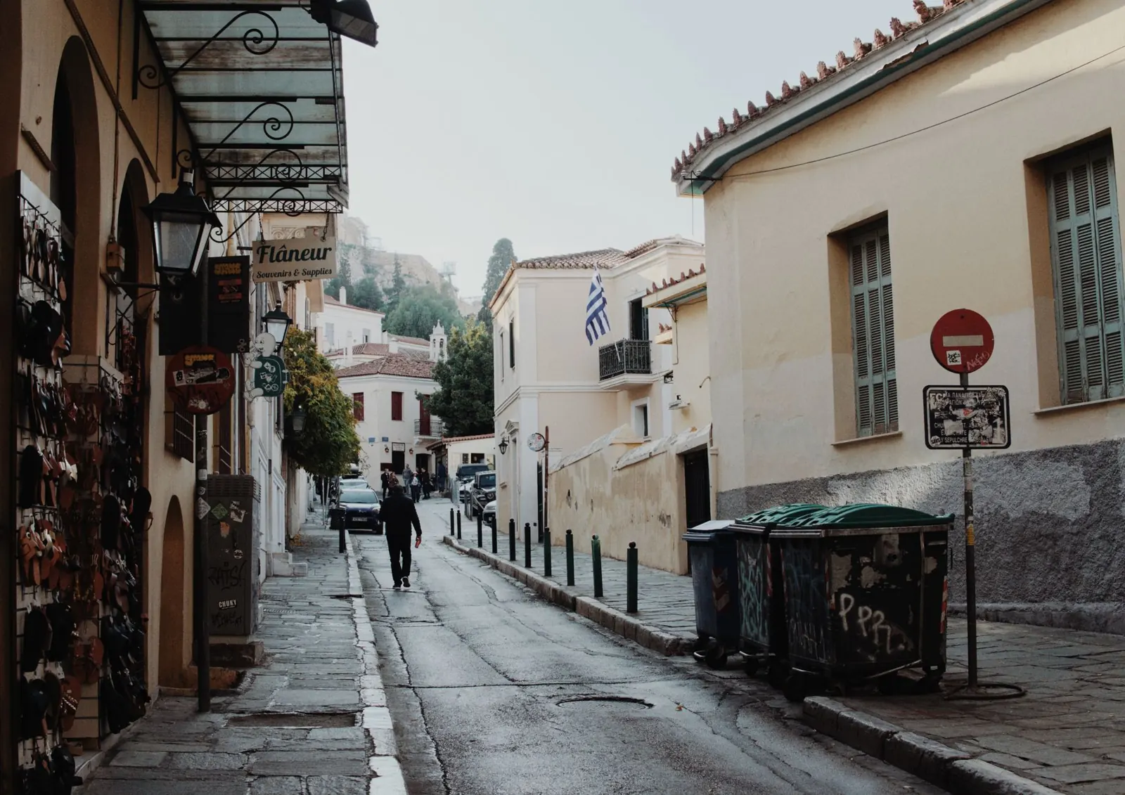 Quiet street in Athens' historic Plaka district with Greek flag and quaint shops.