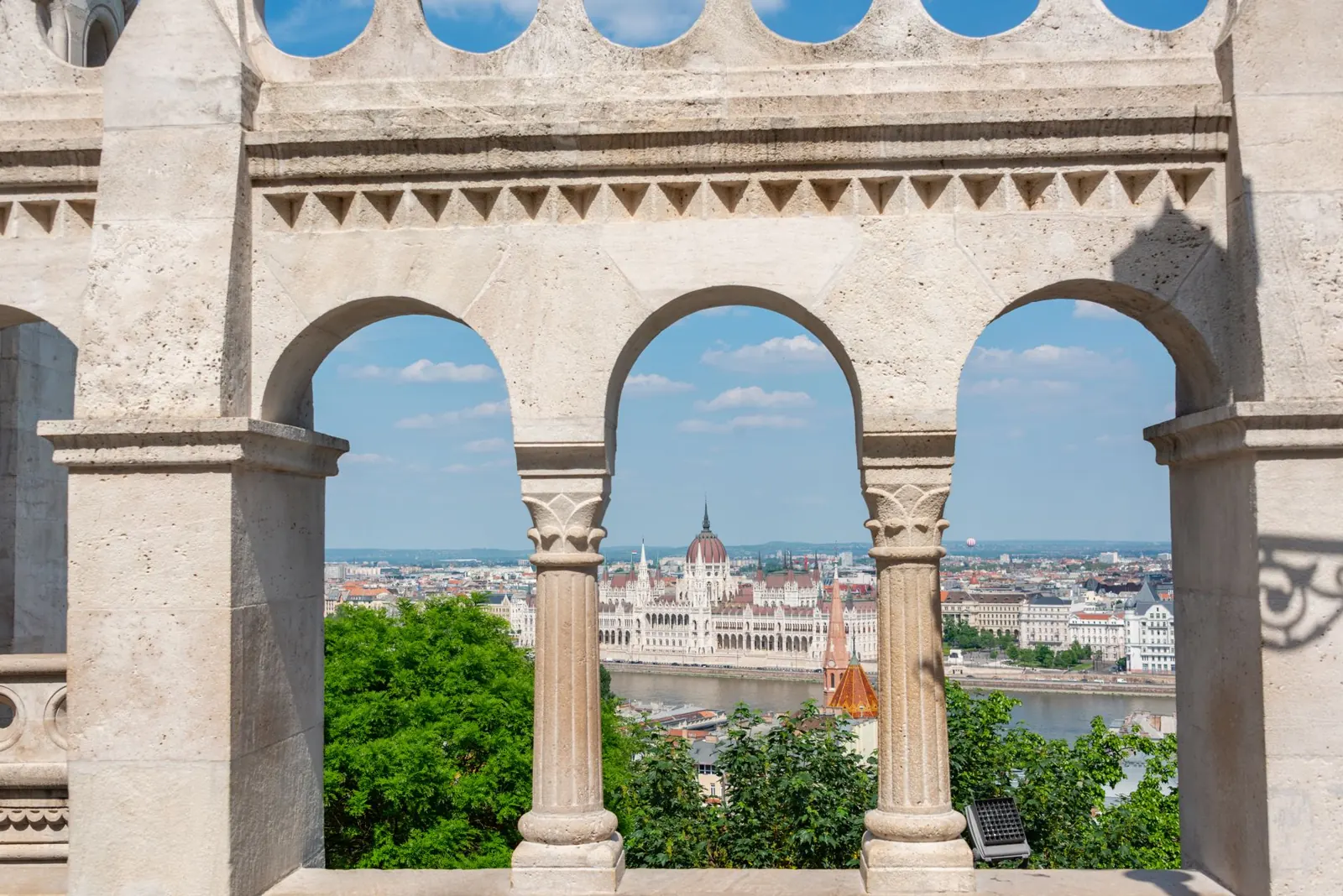 View of Budapest's Parliament Building across the Danube framed by gothic architecture, highlighting urban beauty.