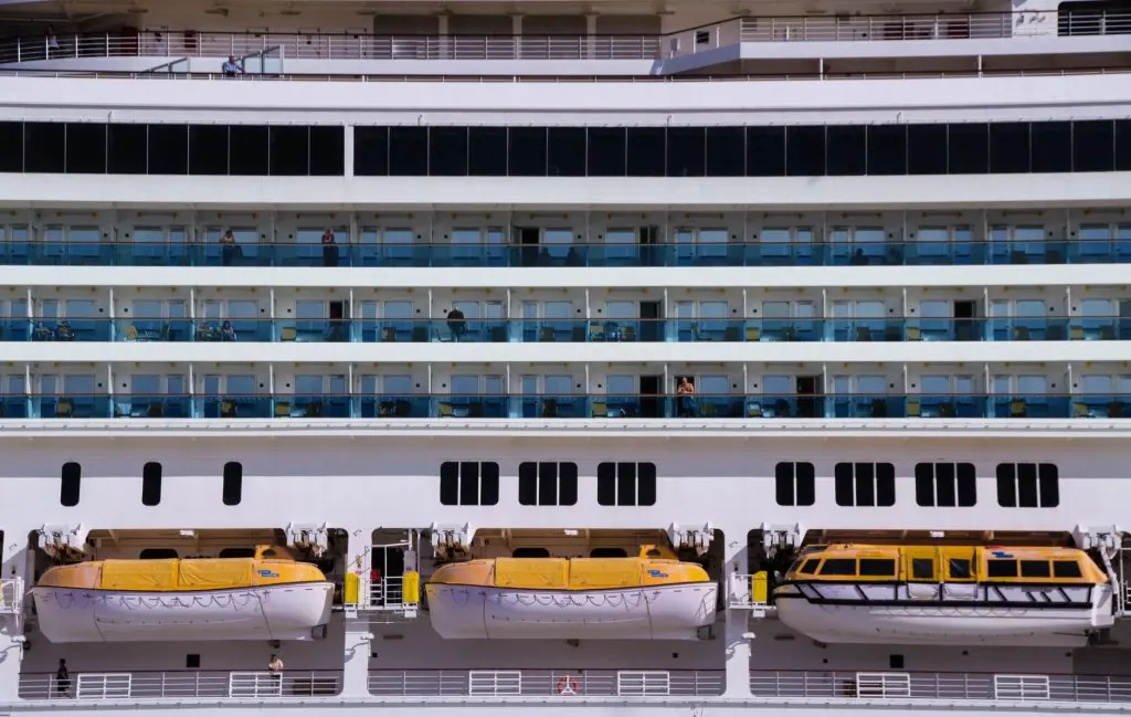 Close-up view of a modern cruise ship showing lifeboats and passenger cabins.