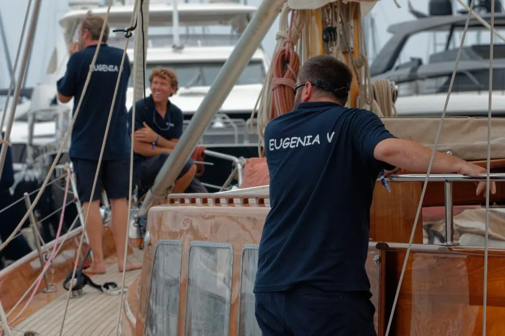 A group of adults preparing a yacht for departure at a bustling harbor.