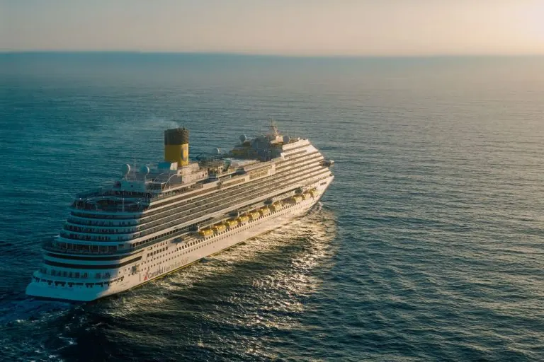 Cruise ship sailing across the ocean at sunset