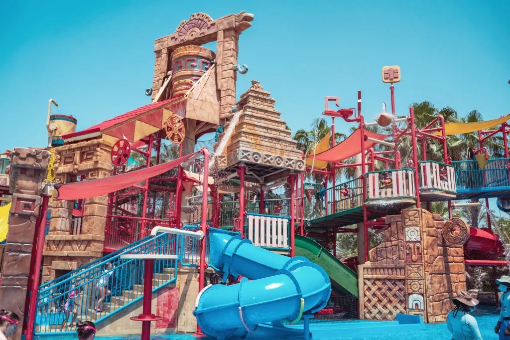 Colorful and lively waterpark featuring slides and artistic structures under a clear blue sky.