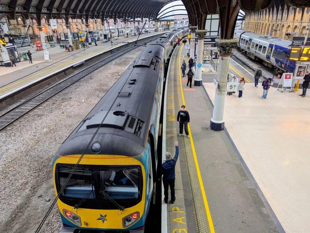 Overhead view of York train station with people on the platform and trains ready for departure.