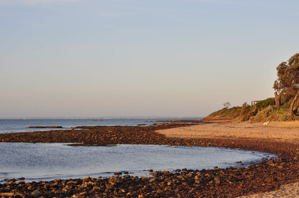 Peaceful view of a rocky beach in Melbourne, Australia, during sunset.