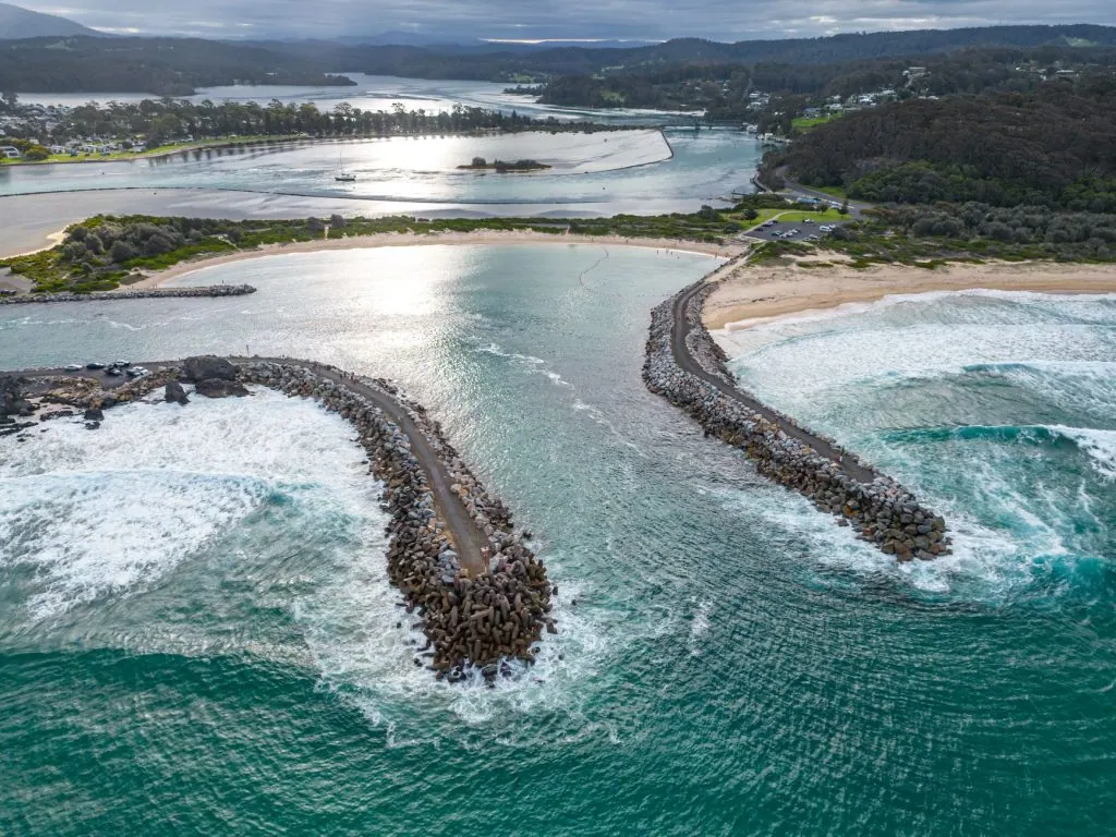 Stunning aerial view of Bermagui Harbor with breakwaters and coastal landscape.