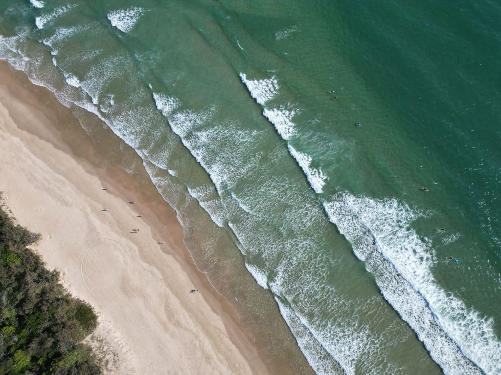 A stunning aerial shot capturing waves and sandy shores at a Queensland beach in Australia.