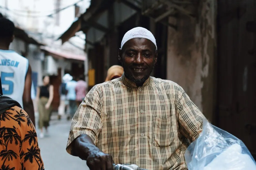 A man rides a bicycle in the bustling streets of Stone Town, Zanzibar.
