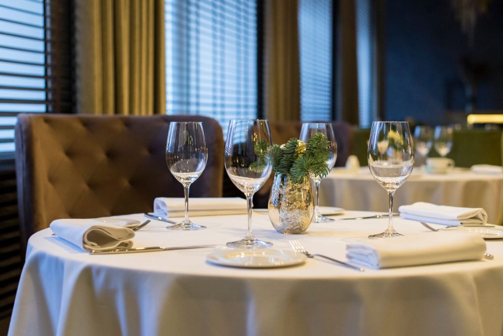 Sophisticated dining setup with polished wine glasses, white napkins, and a decorative centerpiece on a round table.