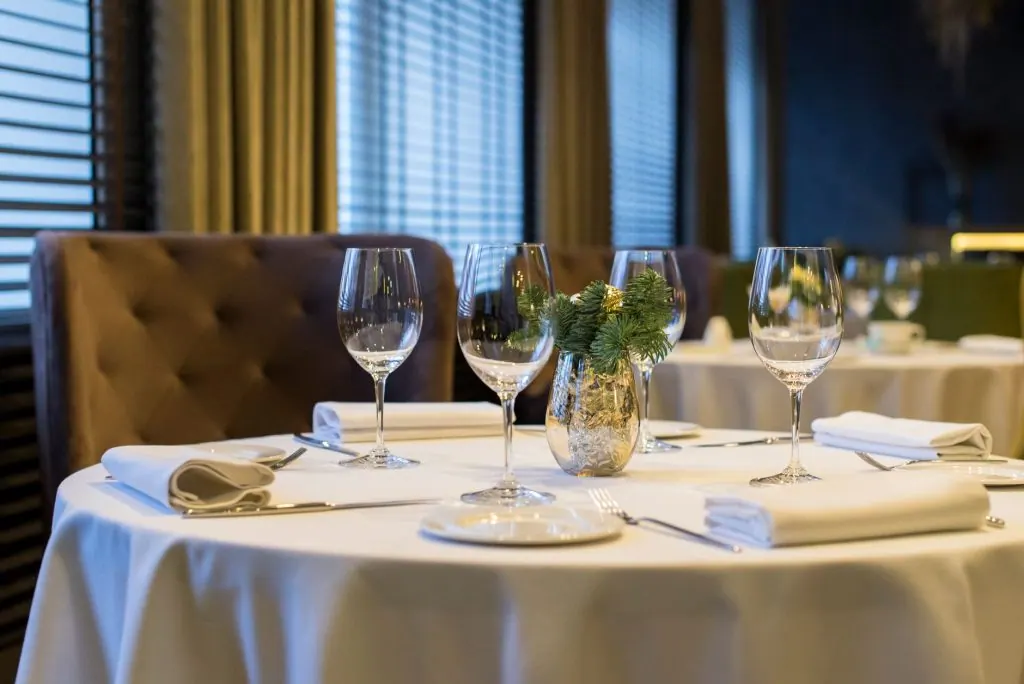 Sophisticated dining setup with polished wine glasses, white napkins, and a decorative centerpiece on a round table.