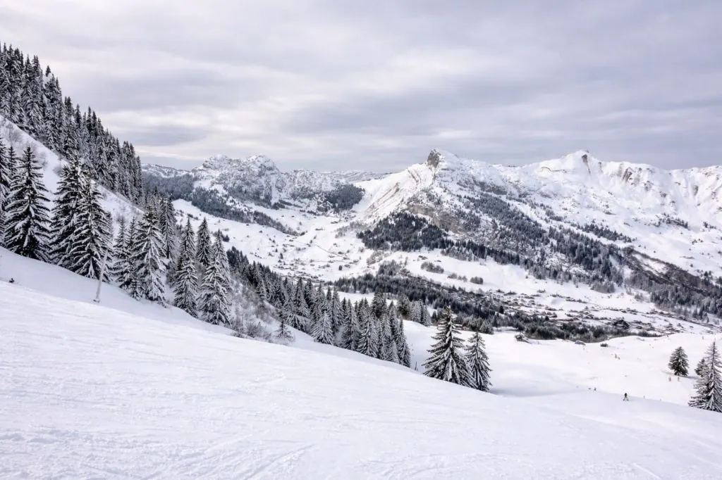 Breathtaking view of snowy mountains and pine trees in Auvergne-Rhône-Alpes, France.