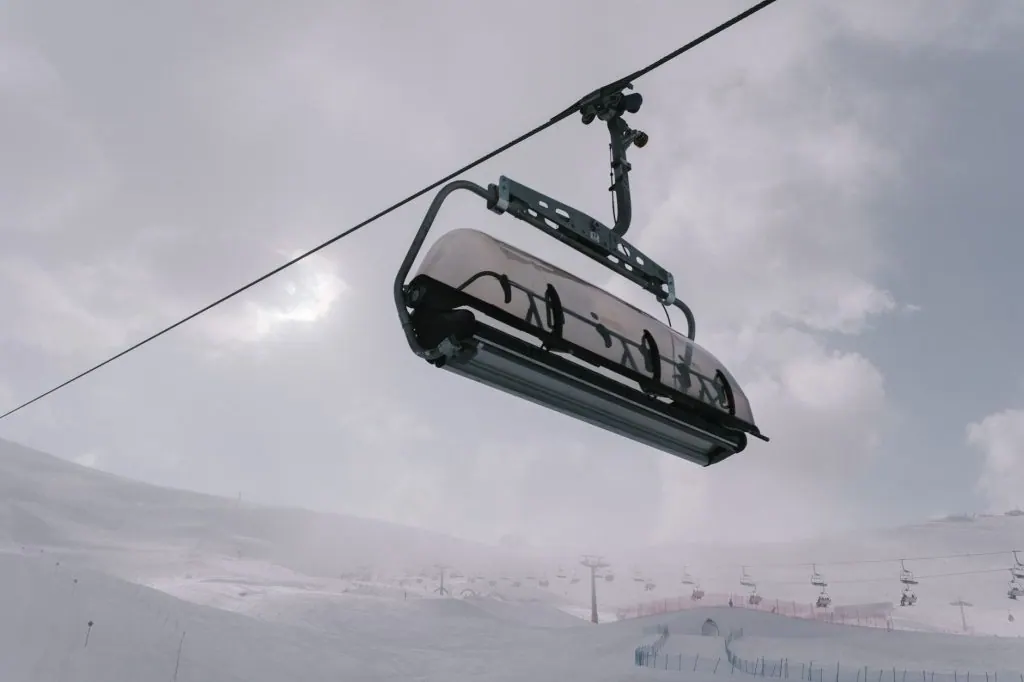 A ski lift captured during winter in Campitello di Fassa, Italy, on a cloudy day.