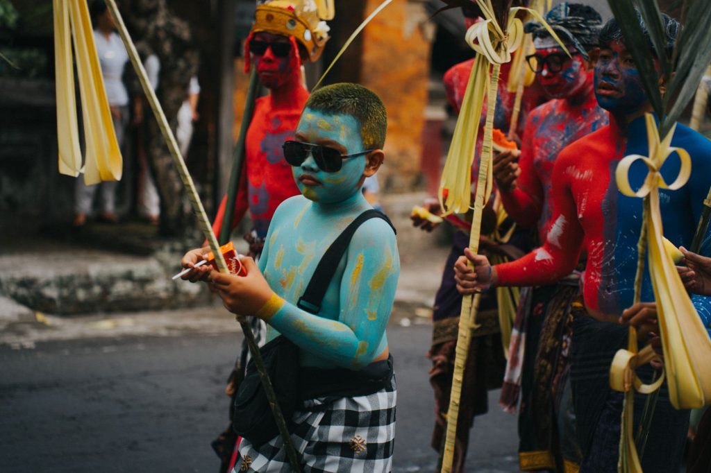 A vibrant cultural parade with participants painted in vivid colors, carrying traditional decorations.