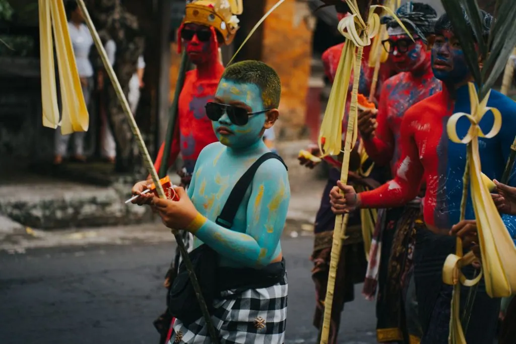 A vibrant cultural parade with participants painted in vivid colors, carrying traditional decorations.