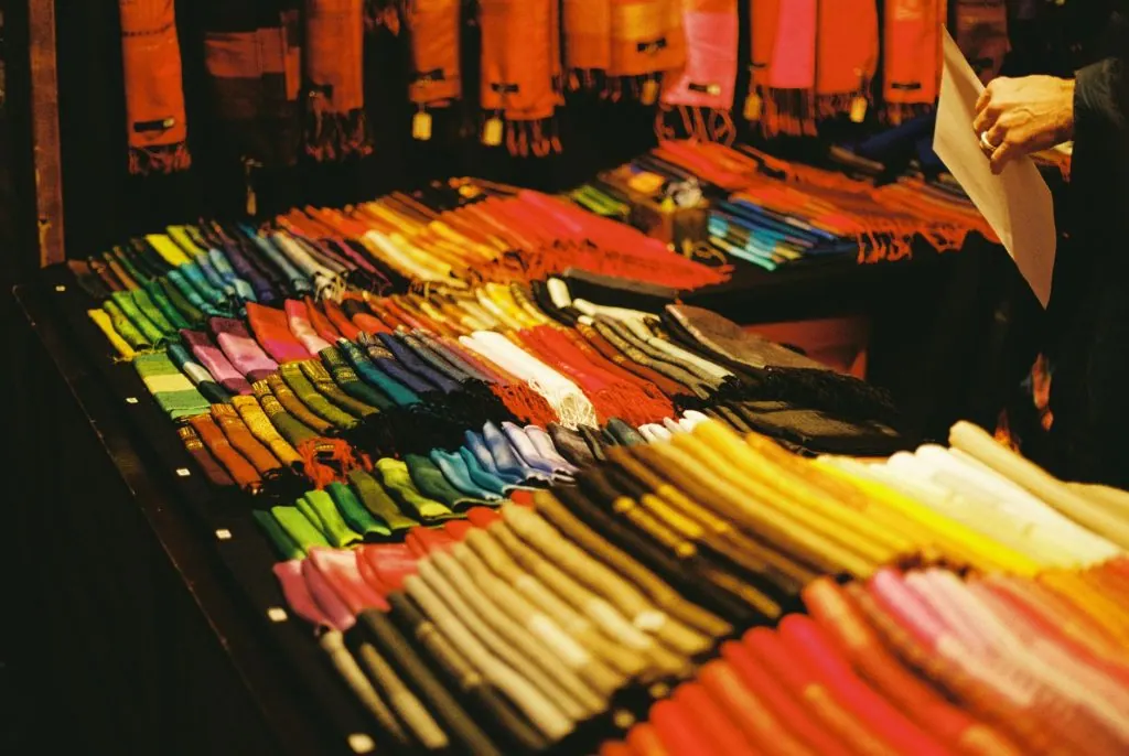 A vibrant display of scarves at a Berlin Christmas market stall, showcasing a variety of colors.