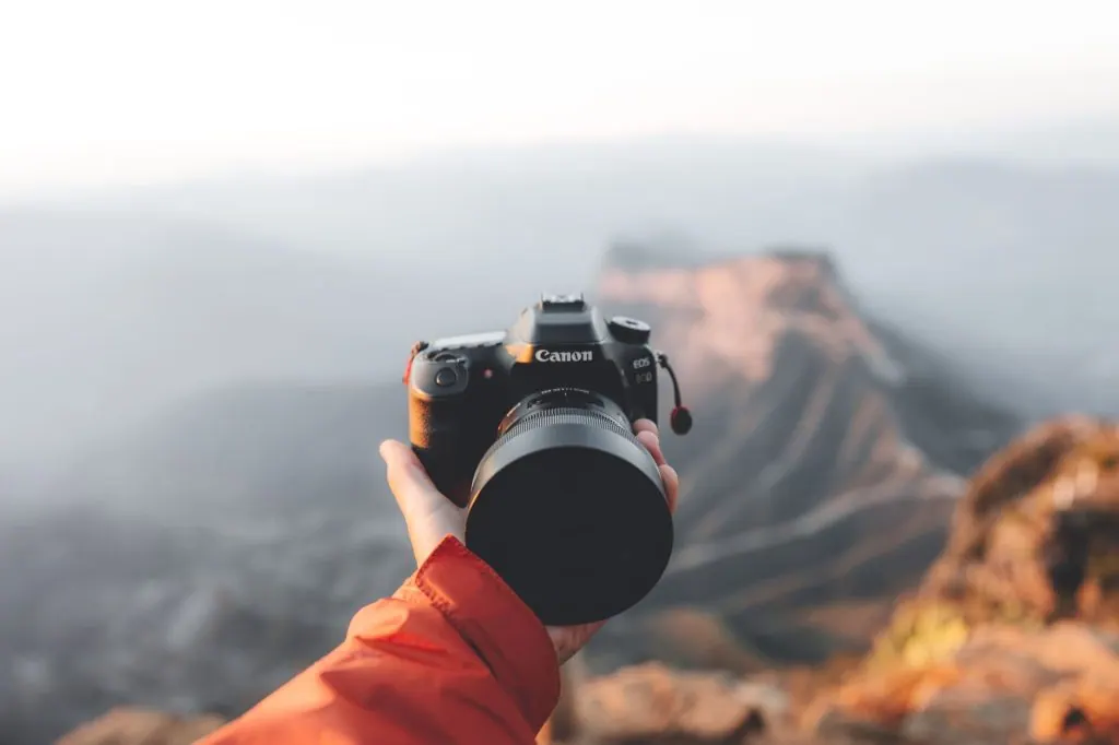 A camera being held with a mountainous background, perfect for photography themes.