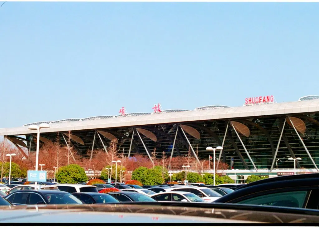 Exterior view of ShuoFang Airport with parked cars and clear blue sky.