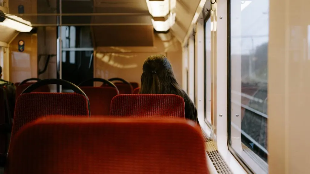 Woman sitting alone on a train, gazing out the window. Capturing solitude and reflection during travel.