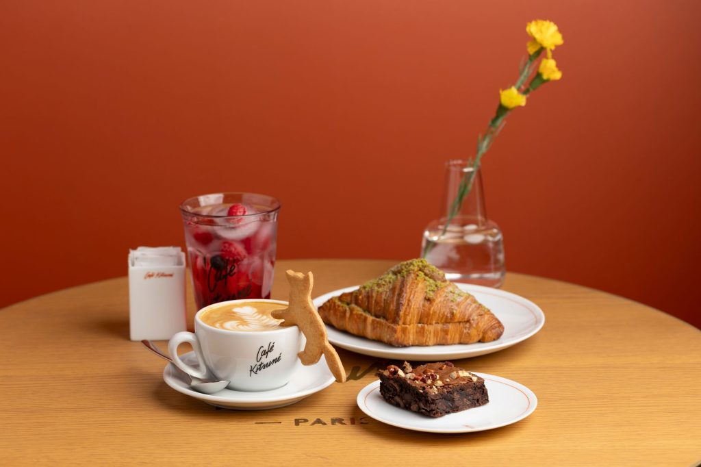 Elegant French café scene with a coffee, croissant, brownie, and iced berry drink.