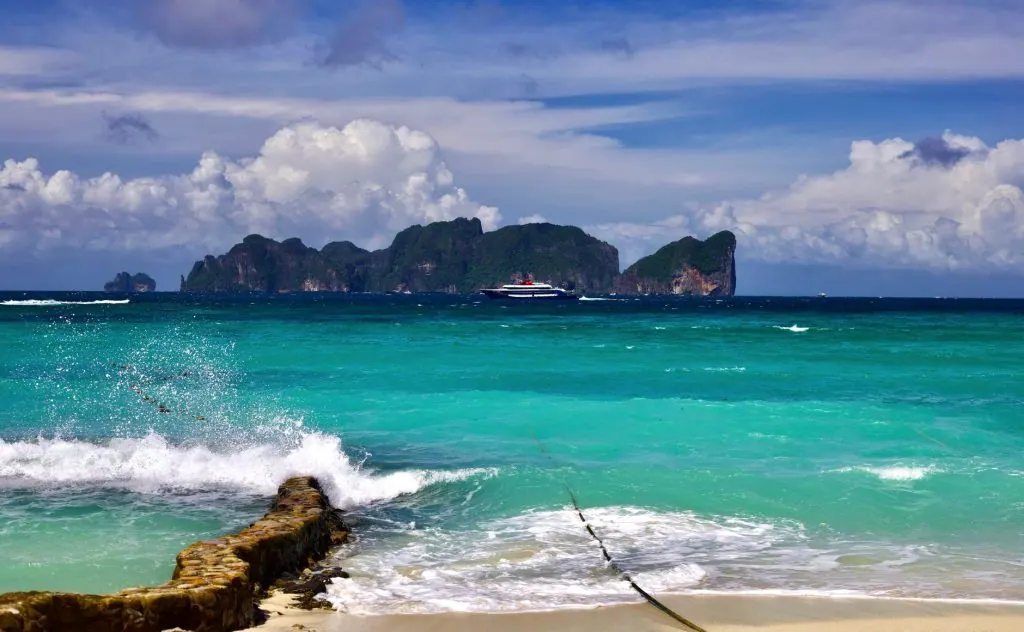 Stunning beach scene with turquoise waters, distant island, and clear skies. Perfect for tropical getaways.