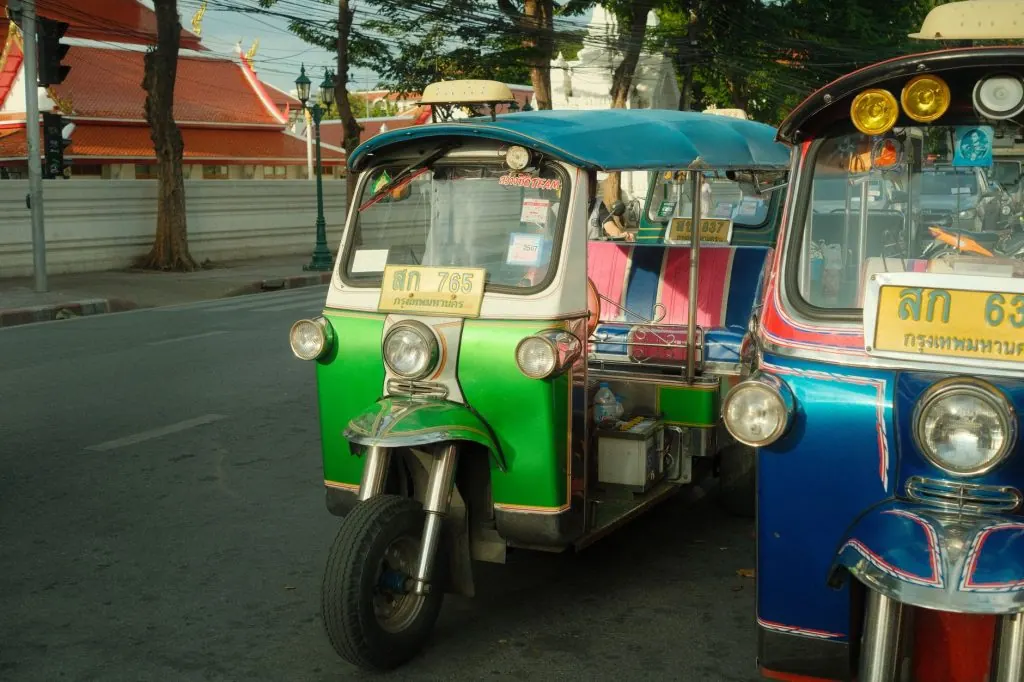Colorful auto rickshaws line a bustling street in Bangkok, capturing urban transportation.