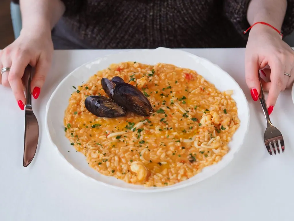 A rich seafood risotto with mussels, served with elegant cutlery.