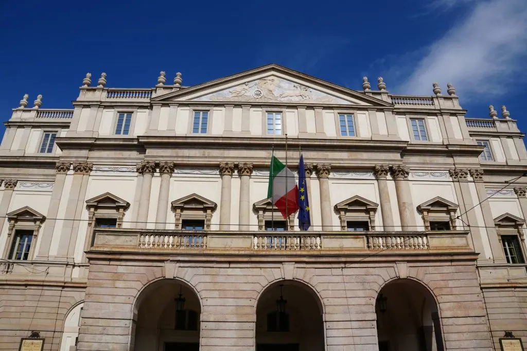 Historic Teatro alla Scala with Italian and EU flags in Milan, Italy.