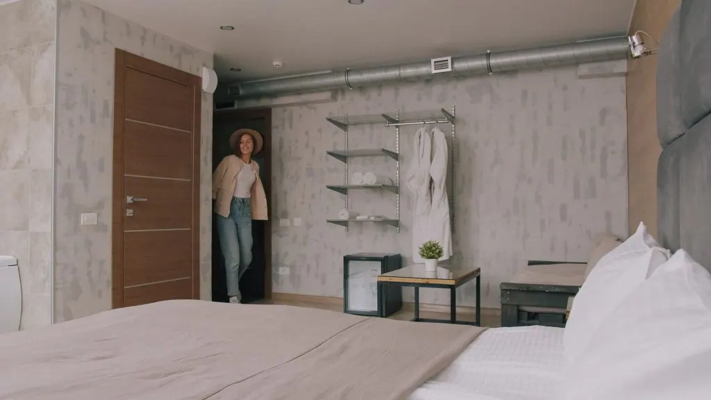 A woman enters a stylish hotel room with contemporary decor and comfortable amenities.