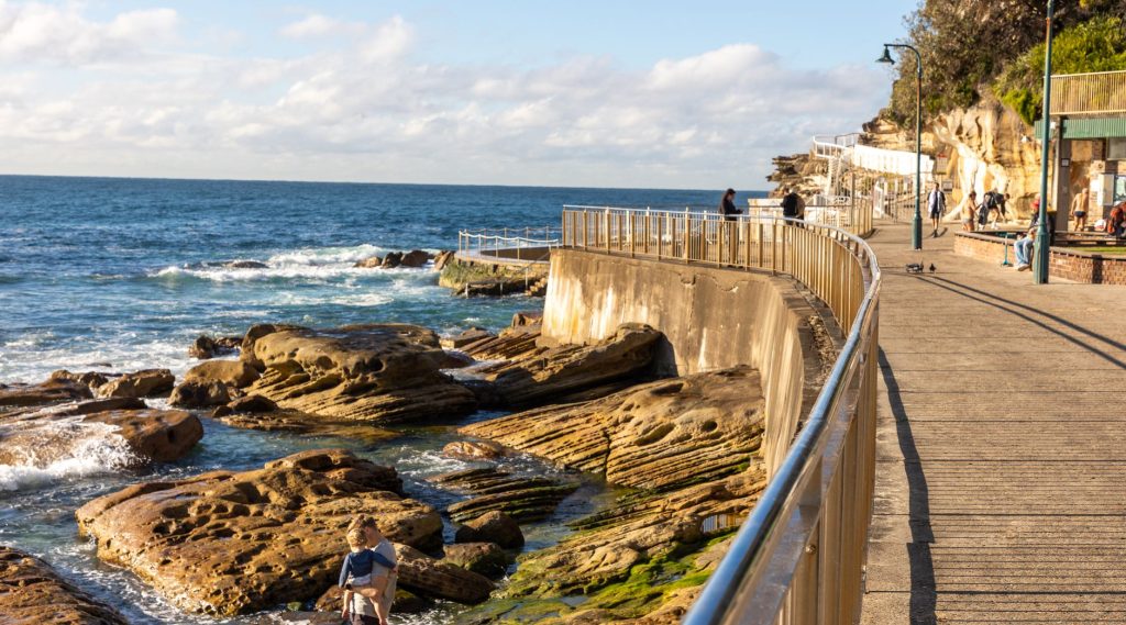 A scenic coastal walkway featuring rugged rocks and the ocean, perfect for leisurely strolls.