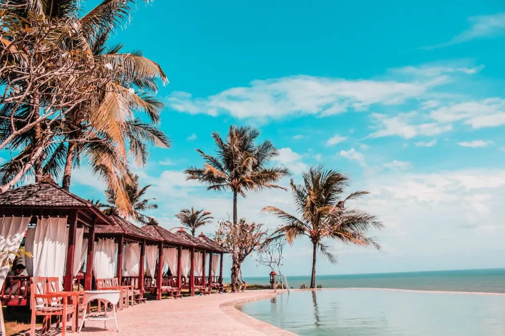 Serene tropical resort featuring palm trees, cozy cabanas, and an exquisite infinity pool by the ocean.