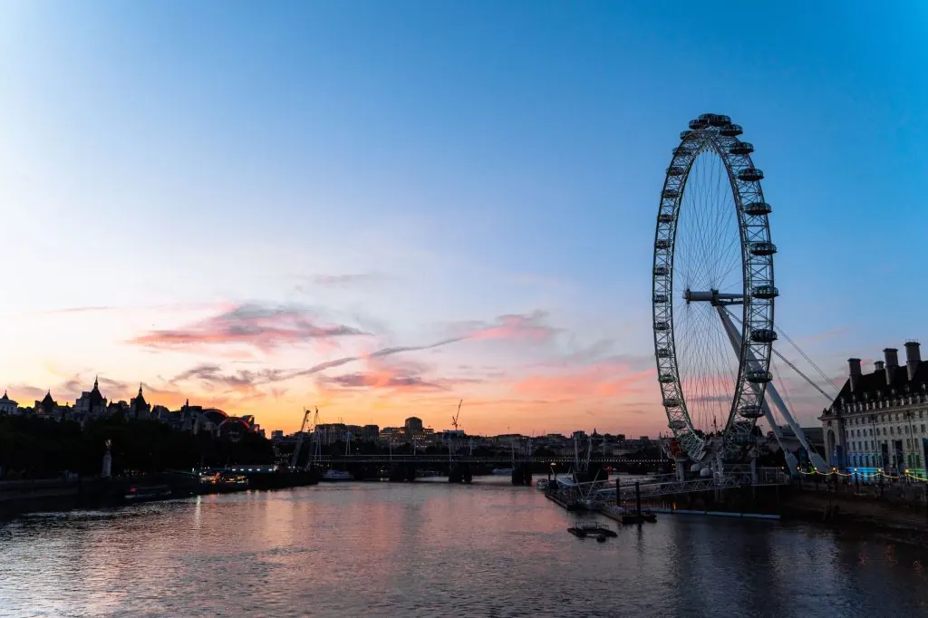 Captivating view of the London Eye at sunset with a dramatic sky over the Thames River.