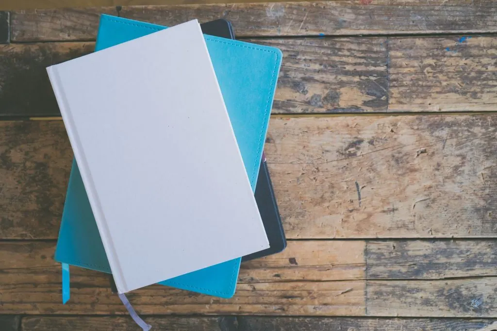 A top view of stacked notebooks on a textured wooden surface, ideal for educational or organizational themes.