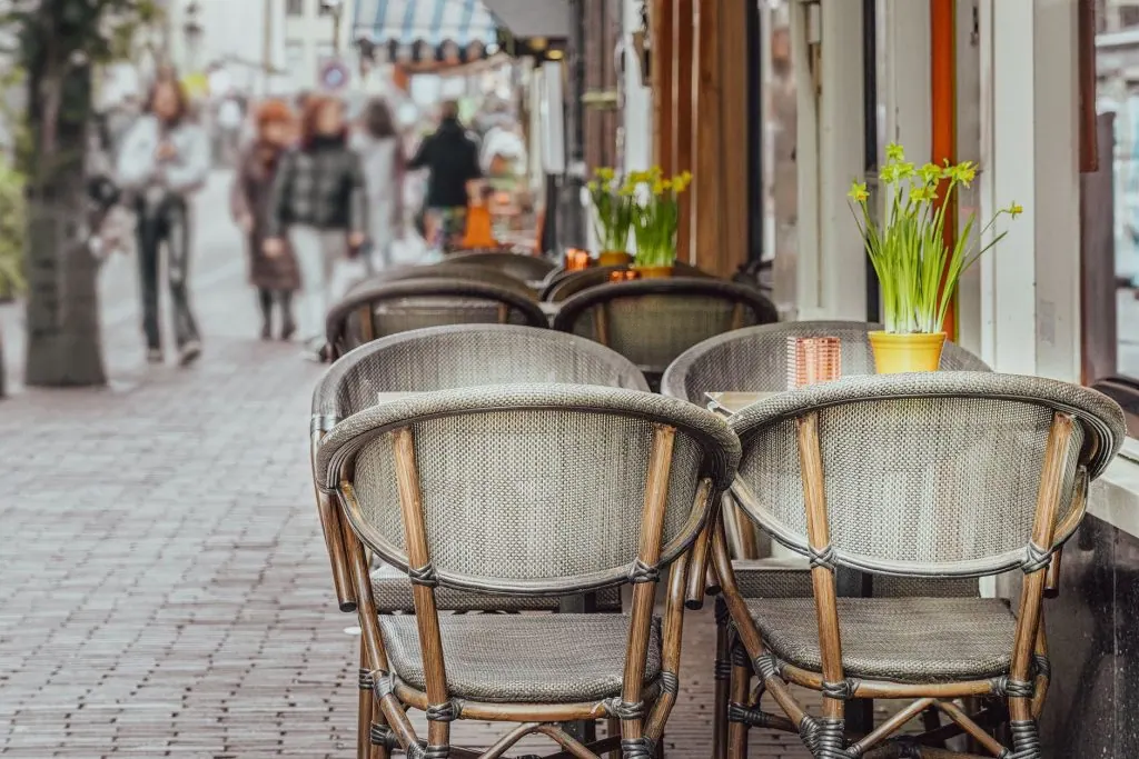 Cozy street café in Amsterdam with outdoor seating, daffodils, and blurred pedestrians.