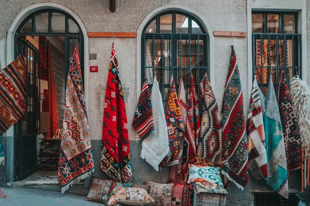 A vibrant display of traditional Turkish carpets hanging in an Istanbul street market.