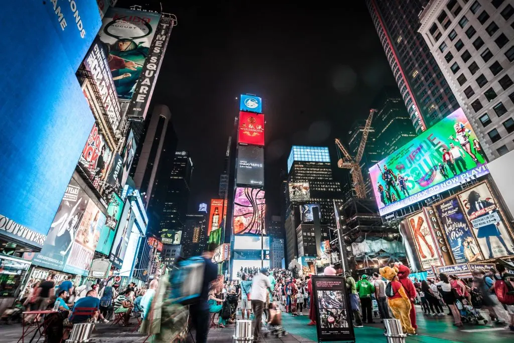 Times Square illuminated at night with bustling crowds and bright billboards in New York City.