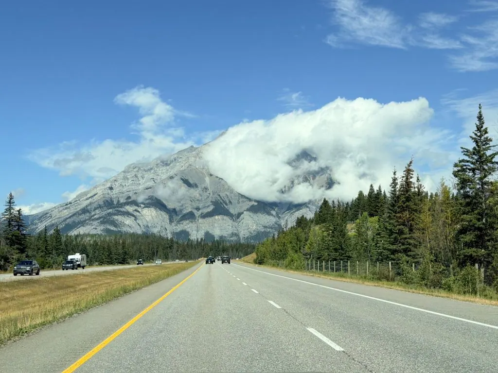 Beautiful landscape view of the Canadian Rockies with a clear highway and blue skies.