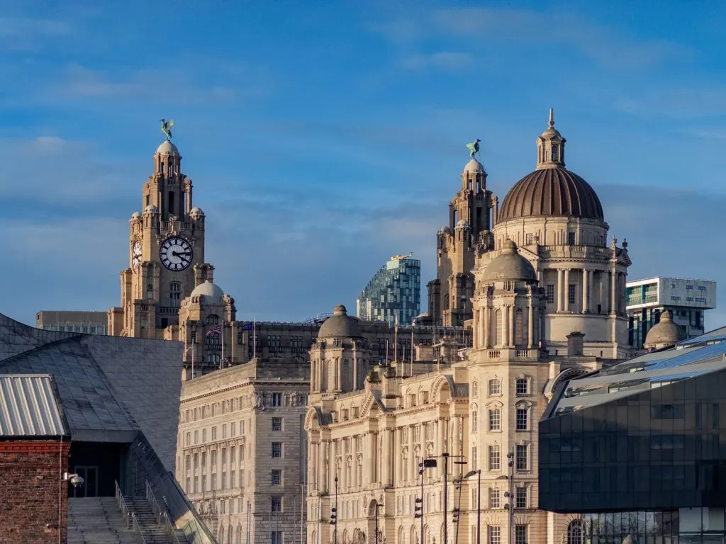 Sunlit Royal Liver Building in Liverpool, showcasing iconic architecture against a vibrant blue sky.