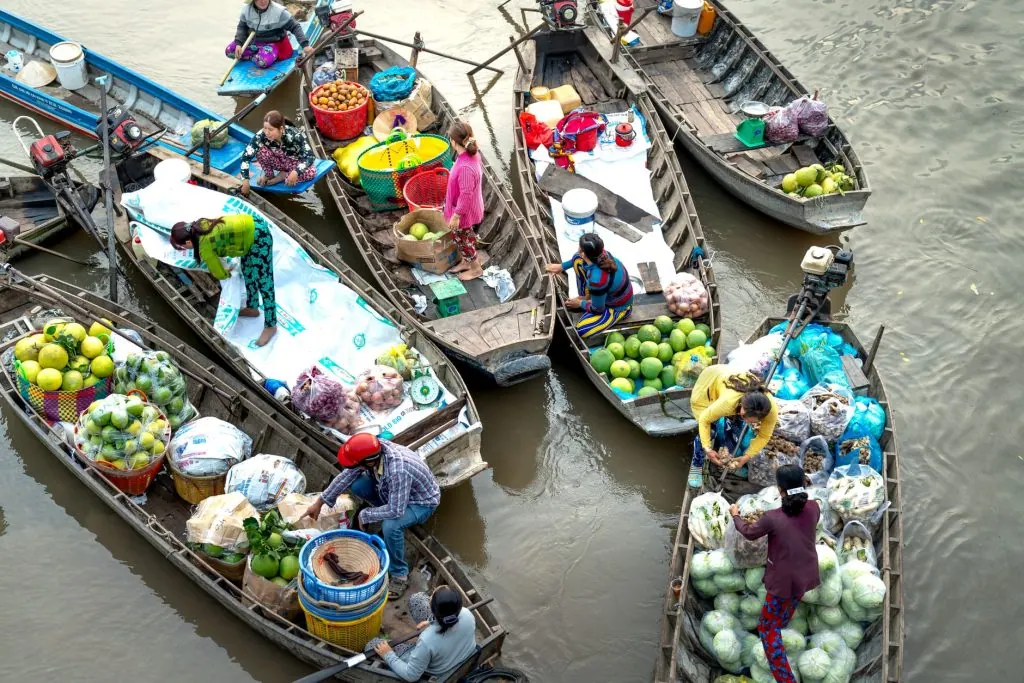 Colorful scene at an Asian floating market with boats filled with fresh fruits and vegetables.