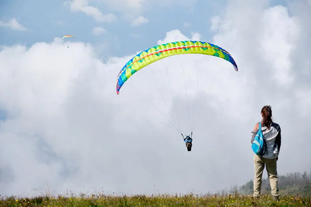 A thrilling paragliding scene with colorful parachute against a cloudy sky.