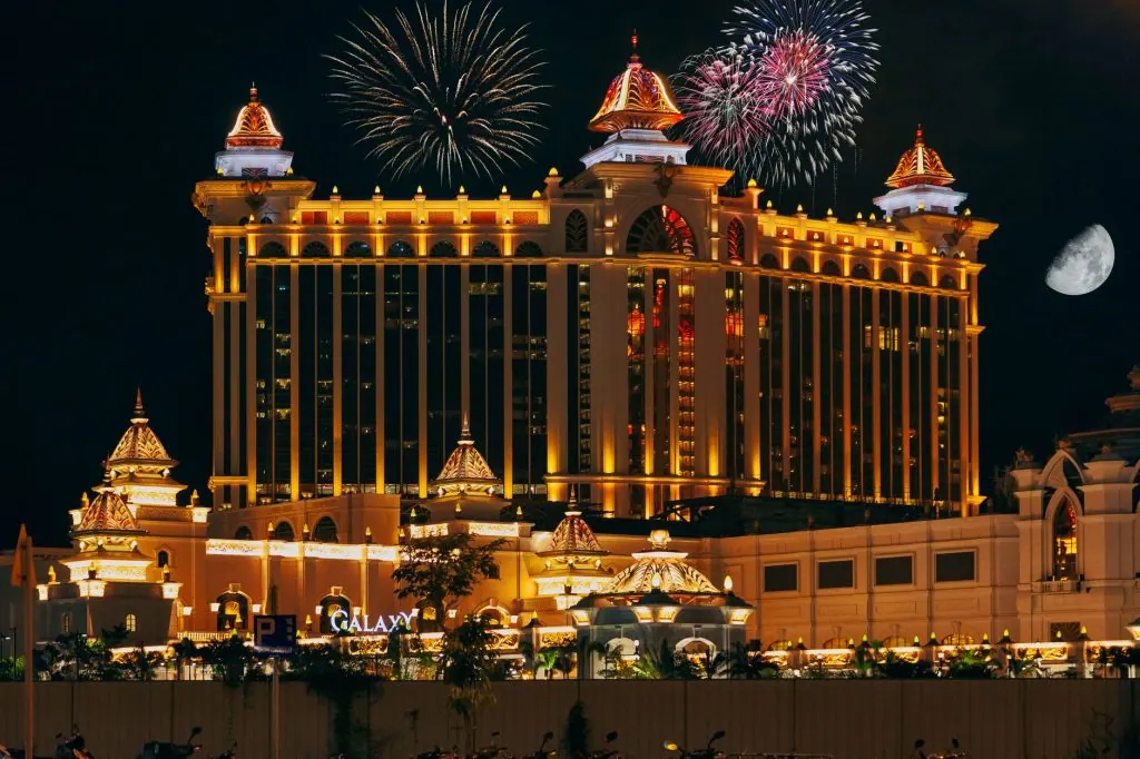 Colorful firework over famous modern palace with illuminated facade and square located in Macau at night