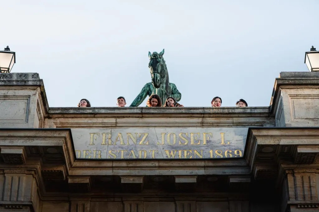 Group of people enjoying the view from Franz Josef I statue in Vienna during sunset.